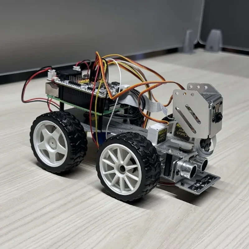The rover from its right front quarter: two white-rimmed wheels along its side, the camera on its tilt bracket and two round range sensors at the nose, jumper wires looped over the boards.