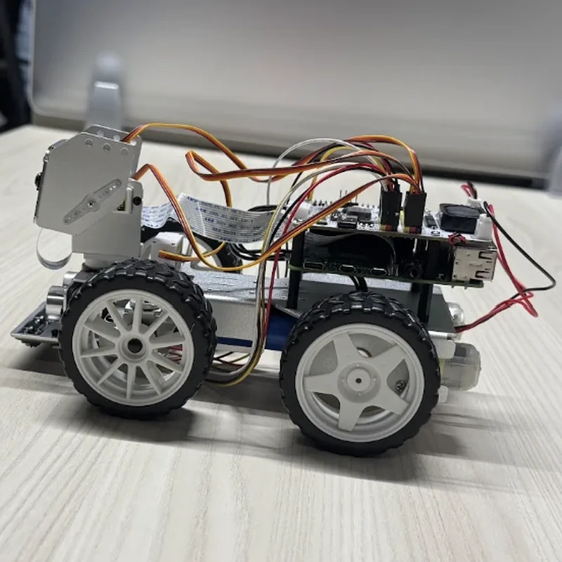 The rover side on, from its left: the camera bracket at the front, the boards and their ports at the back, red and black power leads trailing.