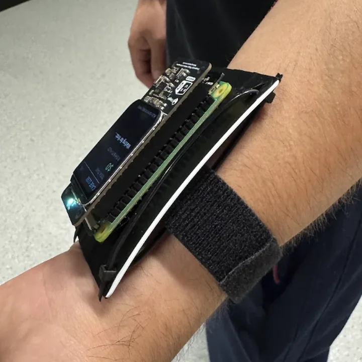 The wrist unit edge on from the right: two boards and the screen stacked on a curved mount, strapped to the forearm.
